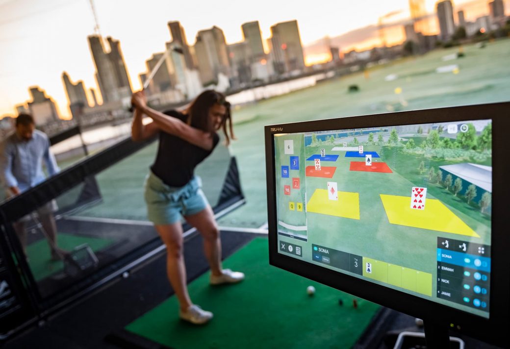 Woman at driving range with Flite screen in foreground